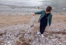 Mali Petar traži školjke na igalskom žalu i vadi plastične kese